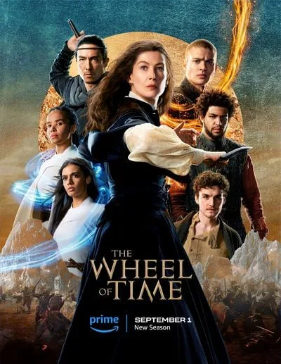 This is a promotional poster for The Wheel of Time Season 2. It shows the ensemble cast, led by Rosamund Pike as Moiraine Damodred. The characters stand in dynamic poses, with flames, glowing light, and a battle scene in the background. The image displays the Prime Video logo and release date.