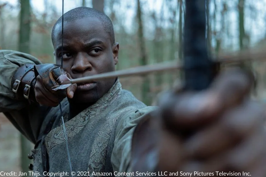 Ihvon, Alanna Sedai’s Warder, draws an arrow with precision, his bow aimed during a tense moment in battle.