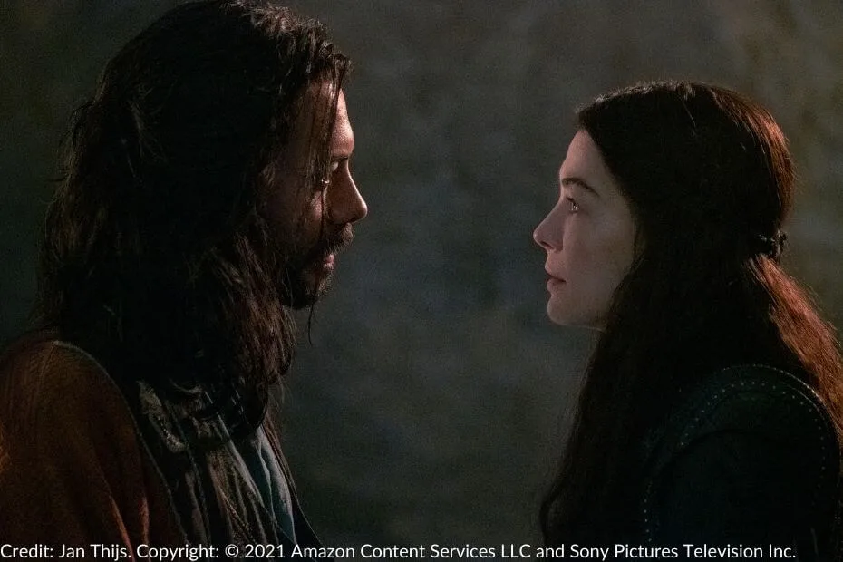 Moiraine and Logain lock eyes in a tense confrontation, their expressions intense.