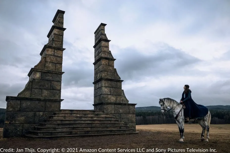 Moiraine sits atop her gray mare, Aldieb, gazing at the towering stone Waygate with its monolithic pillars and steps leading to the open portal.