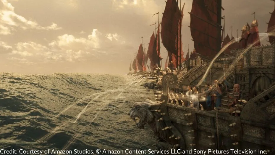 A fleet of Seanchan ships sails on a turbulent sea as women aboard an armored ship channel the One Power, creating towering streams of water and an impending tsunami.